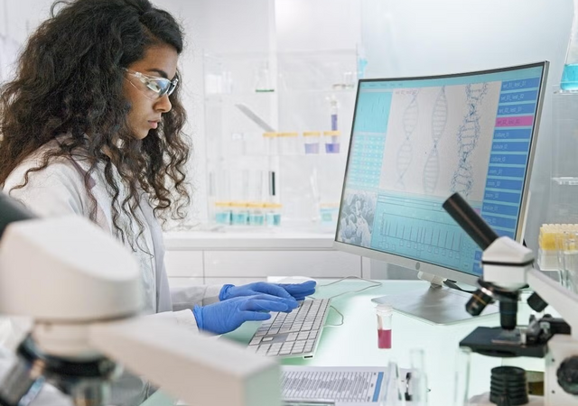 A person wearing gloves and typing on a keyboard in a medical setting