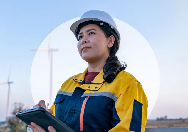 A person wearing a hard hat and holding a tablet