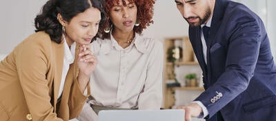 Three people reviewing content on a monitor