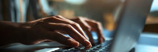 Closeup of hands typing on a laptop keyboard