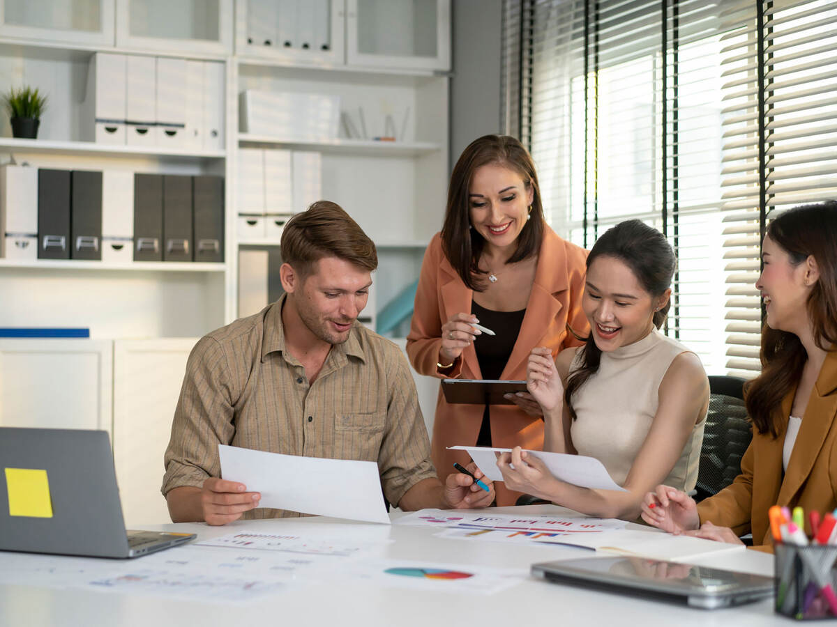 Four happy people working at a table together