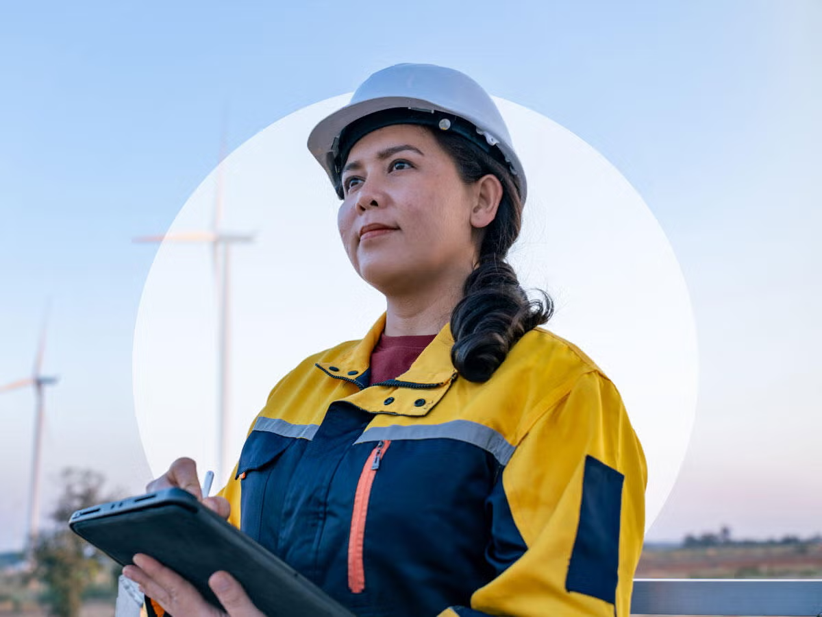 A person wearing a hard hat and holding a tablet