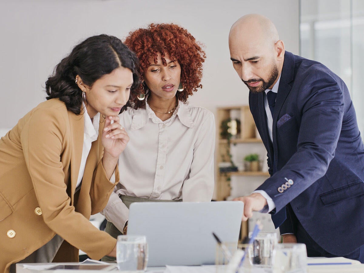 Three people reviewing content on a monitor