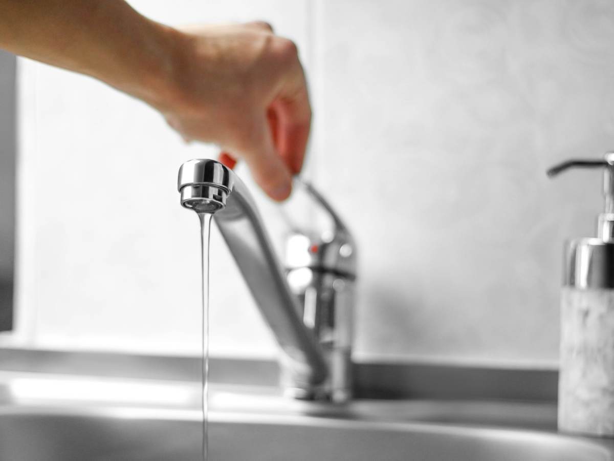 Hand opens water tap close-up